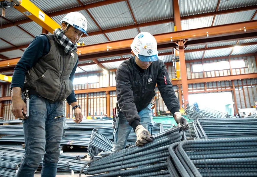 工場内で鉄筋を検査する作業員